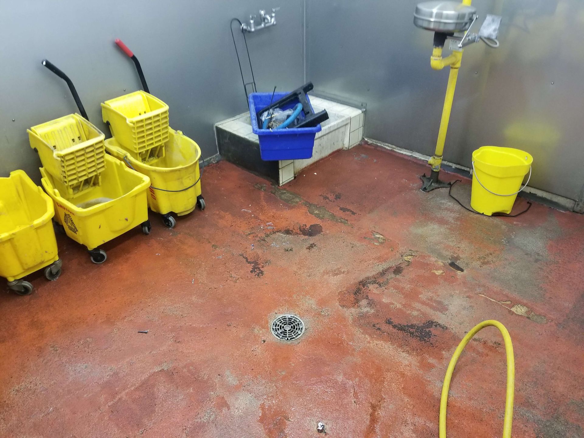 A room with yellow mop buckets and a sink.