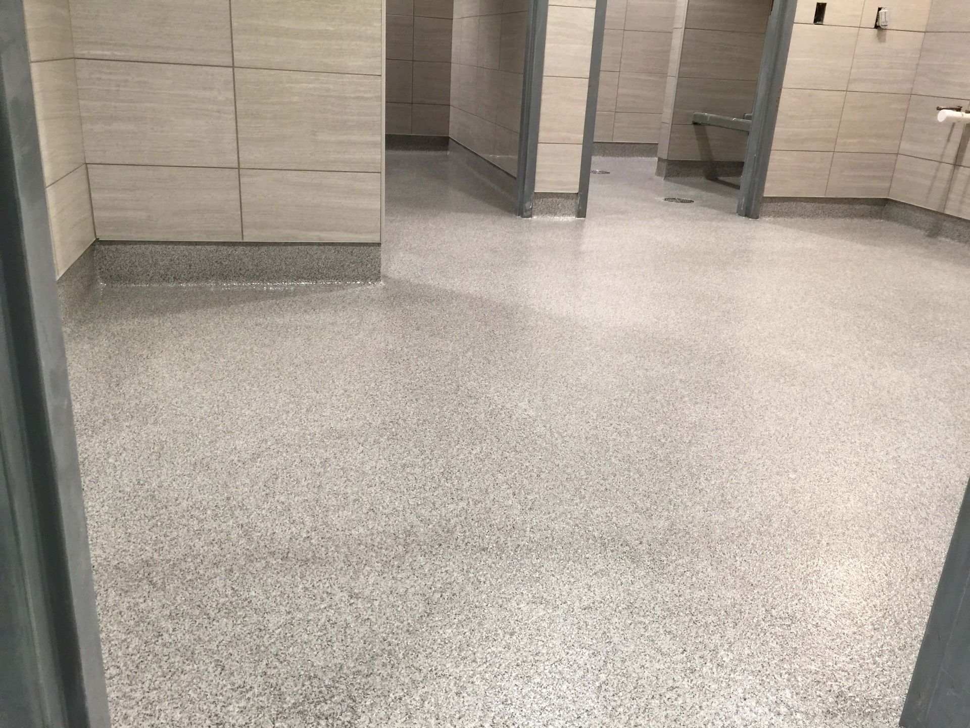A bathroom with a gray floor and white tiles.