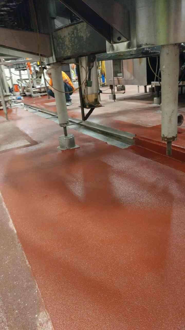 Red industrial floor with metal machinery; factory interior.