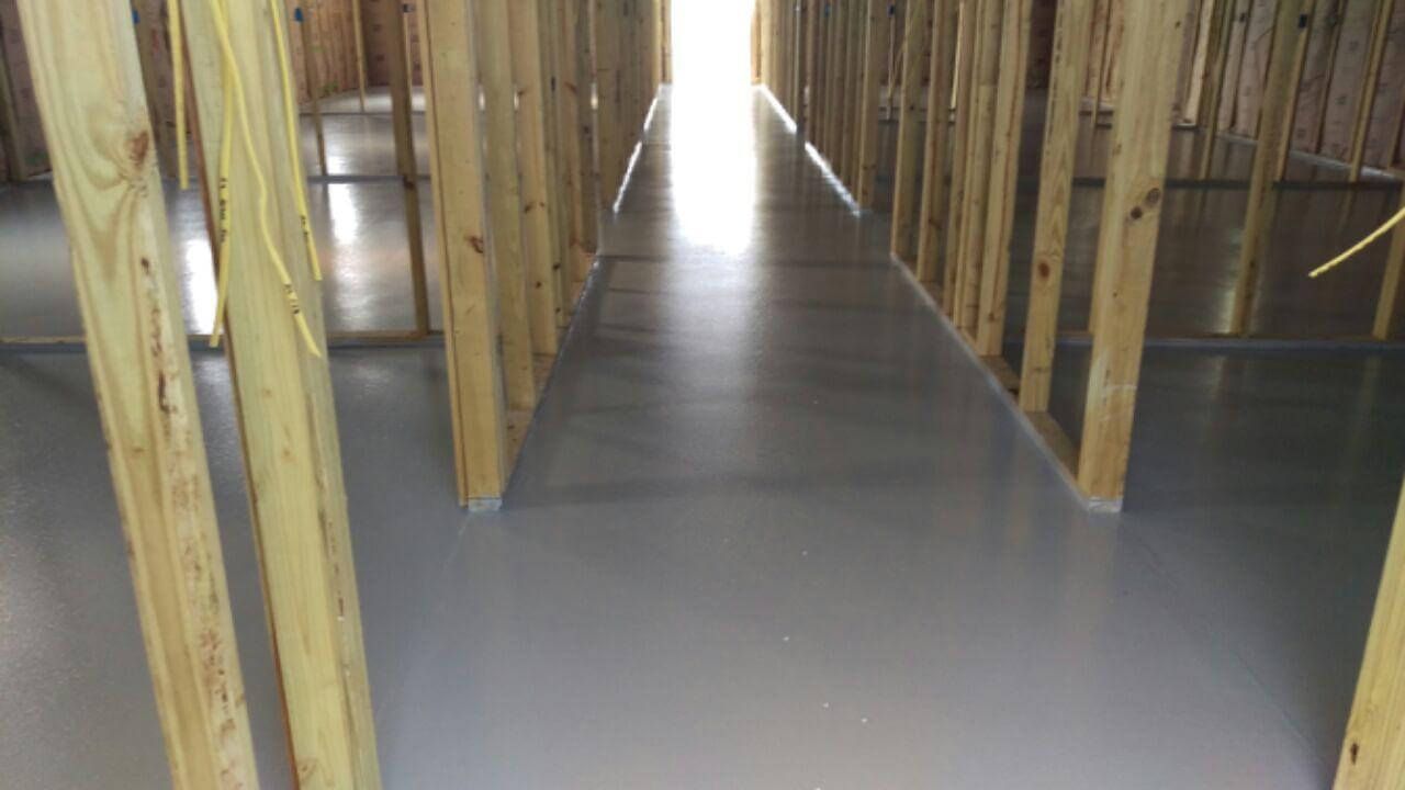 Wooden framing surrounds a long, gray, polished floor with bright light at the end.