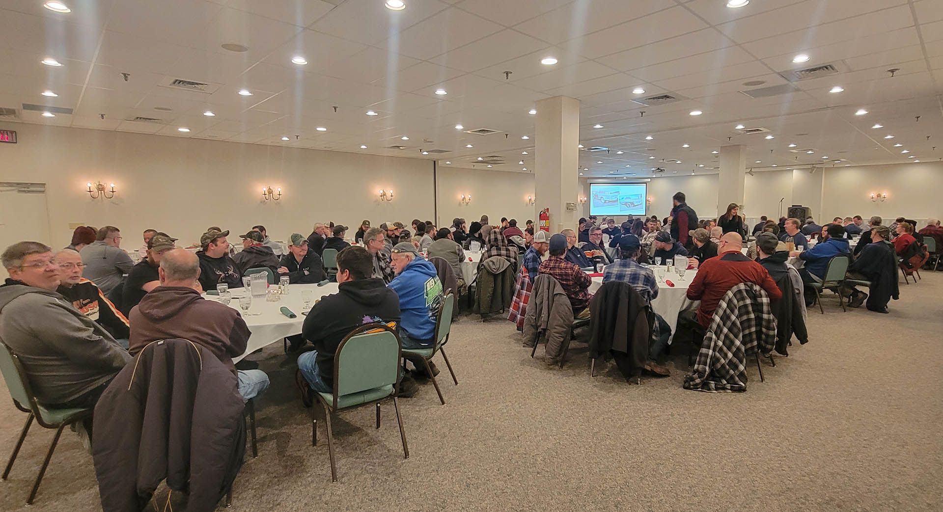 A large group of people are sitting at tables in a large room.