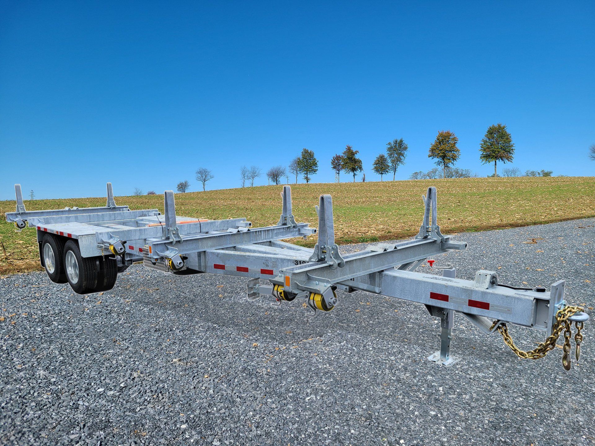 A trailer is parked on a gravel road next to a field.
