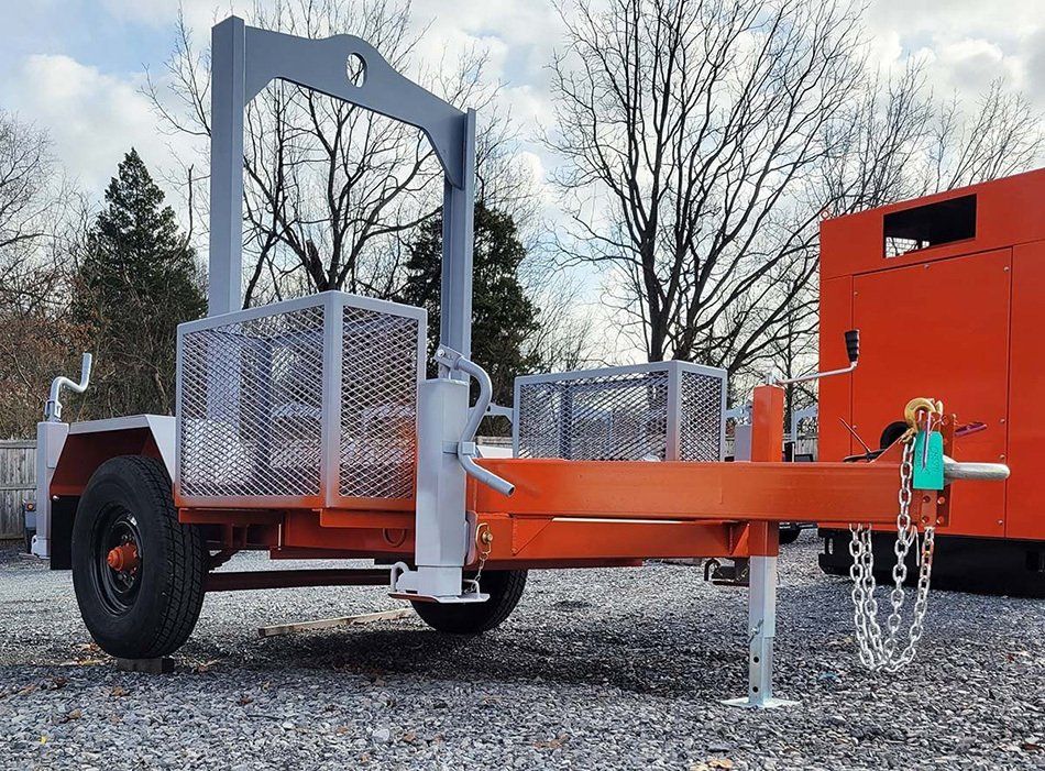 An orange trailer is parked in a gravel lot next to an orange truck.