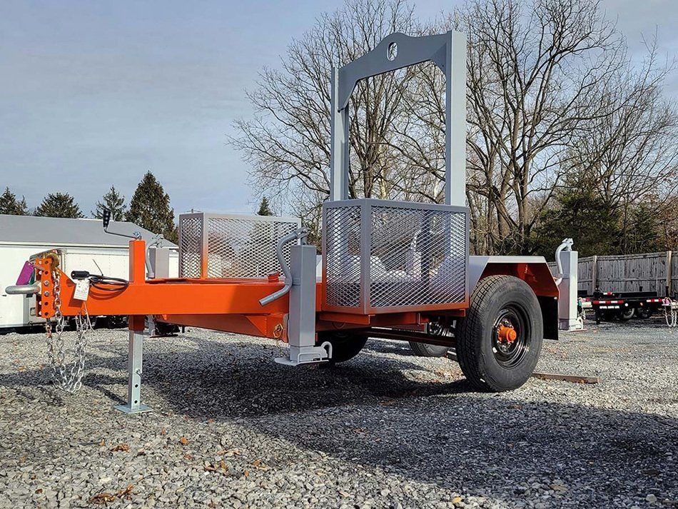 A trailer is parked in a gravel lot with trees in the background