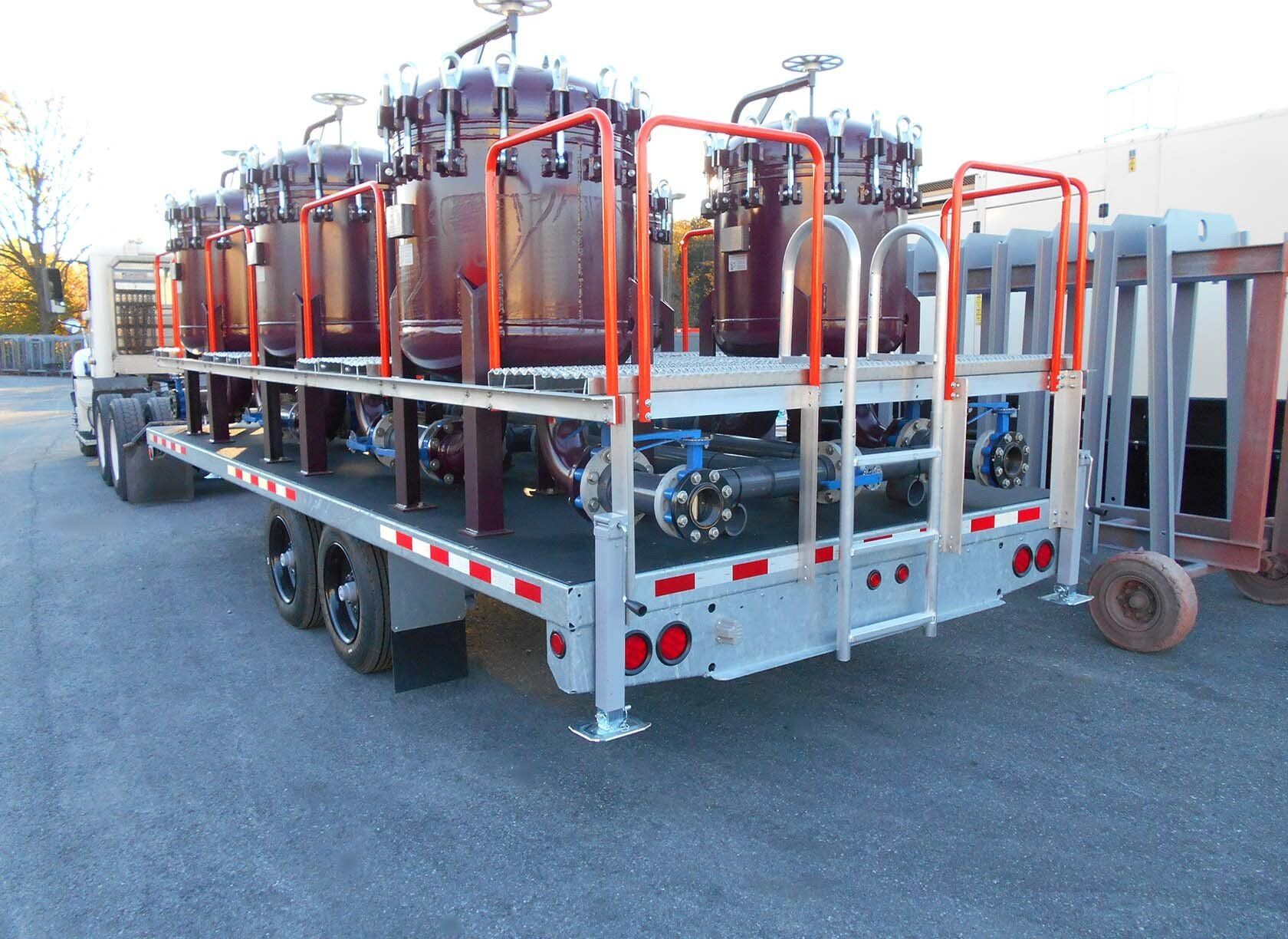 A semi truck is carrying a trailer with a ladder on it