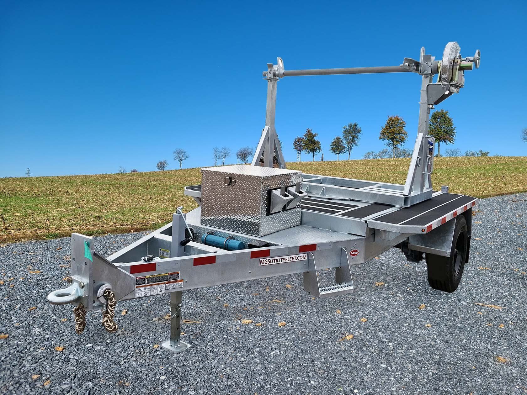 A trailer is parked on a gravel road next to a field.