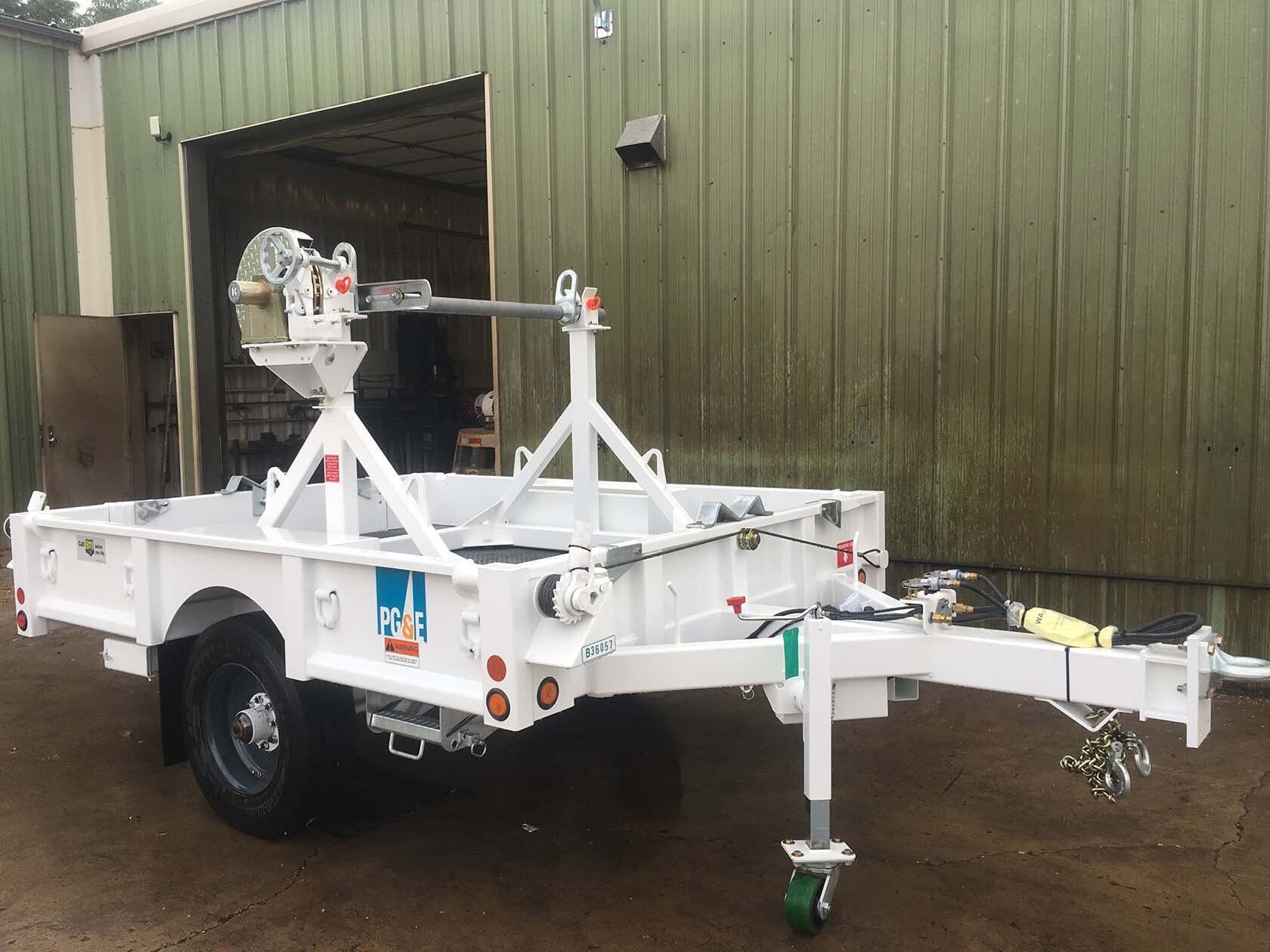 A white trailer is parked in front of a green building.