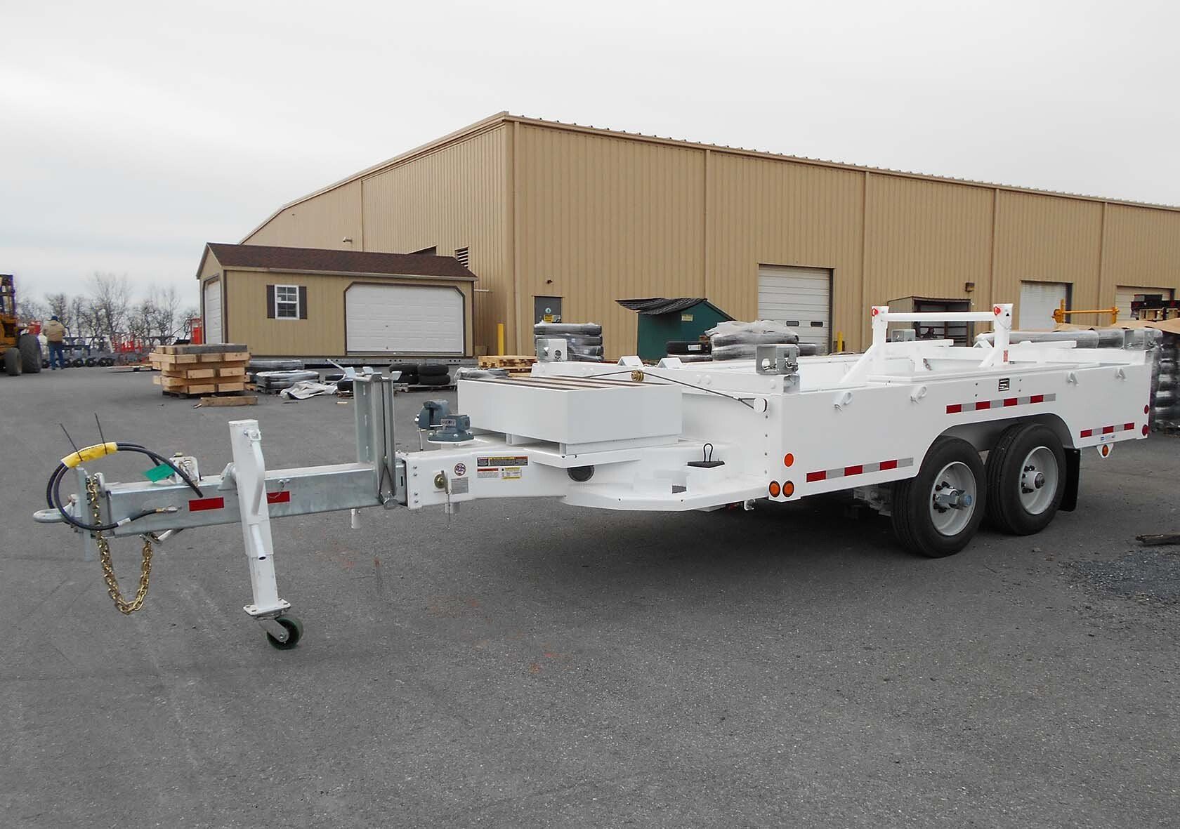 A white trailer is parked in front of a building