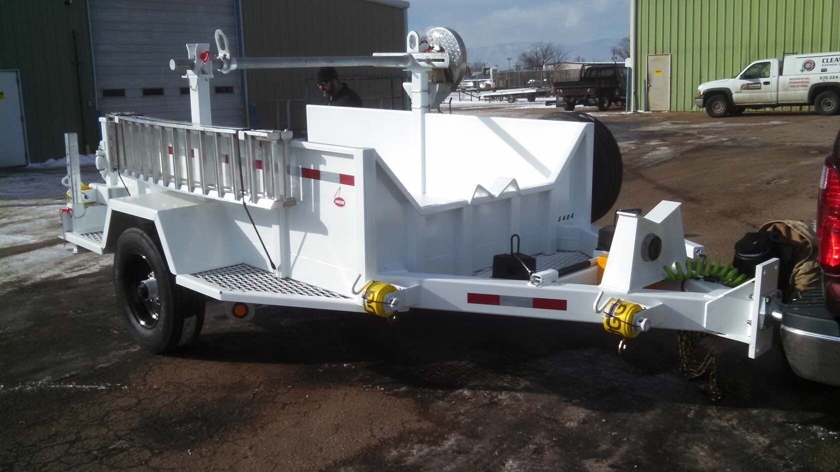 A white trailer with a ladder attached to it