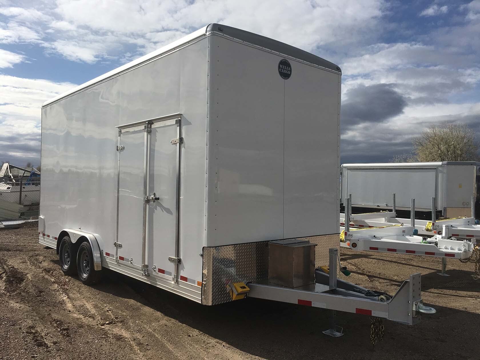 A white trailer is parked in a dirt field.