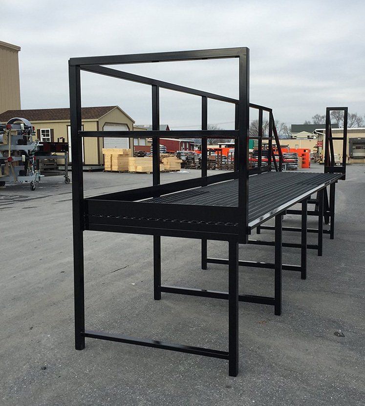 A metal platform with a railing is sitting in a parking lot