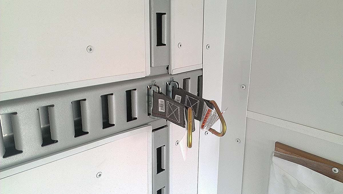 A spider is hanging from a metal bar on a wall.