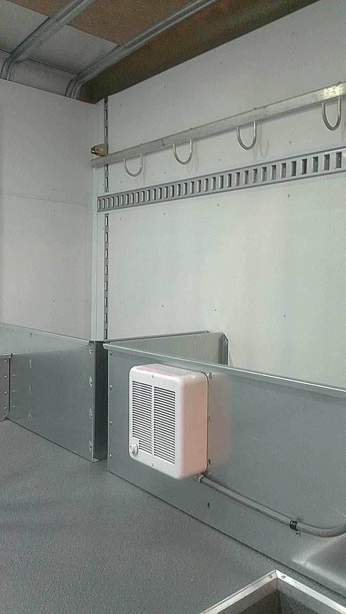 A kitchen with a sink and a fan on the wall.