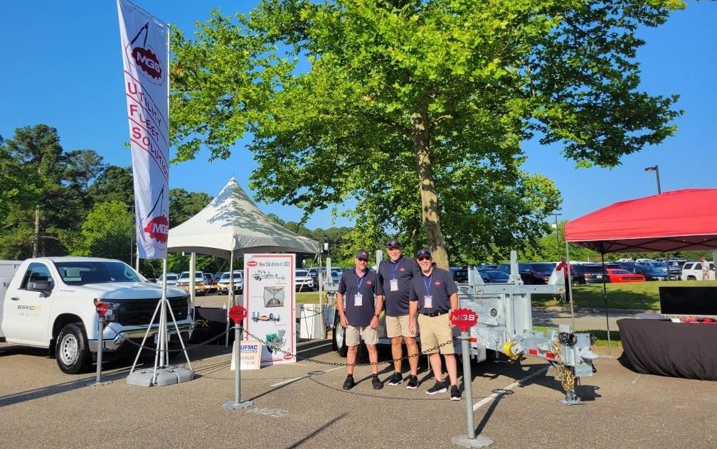A group of men are standing in front of a trailer in a parking lot.