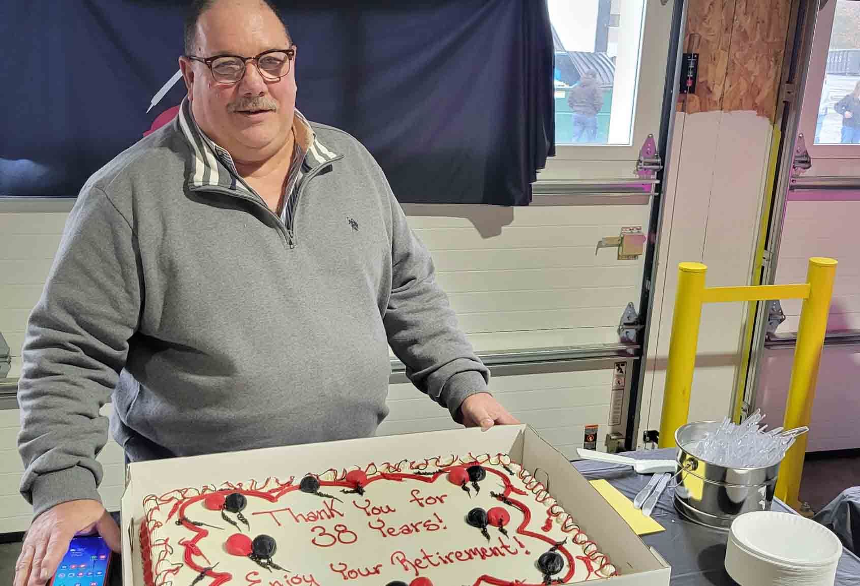 A man is standing in front of a cake that says thank you for 30 years.