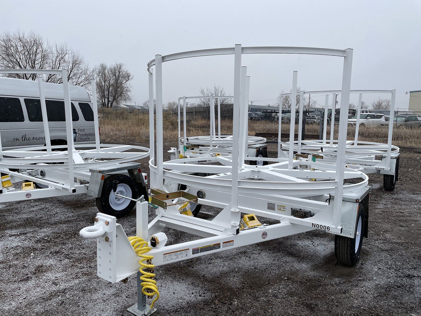 A bunch of white trailers are parked in a field.