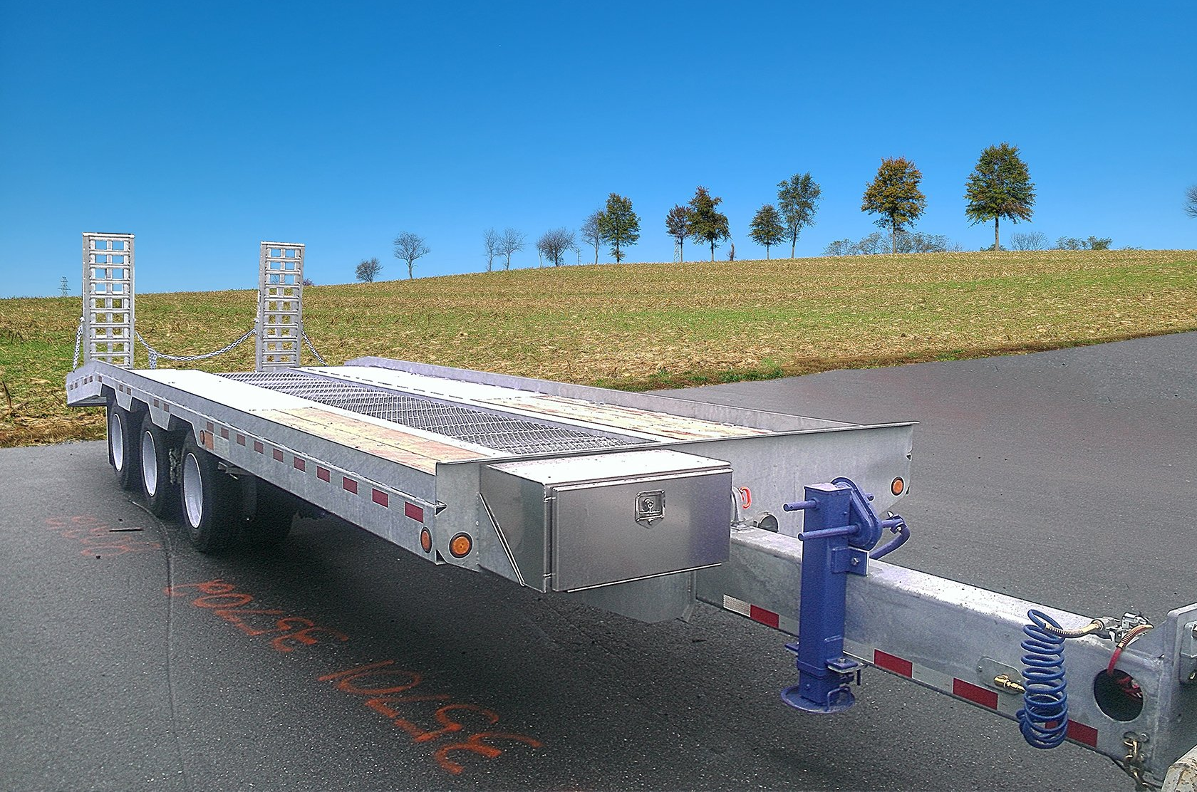 A trailer is parked on the side of the road with trees in the background