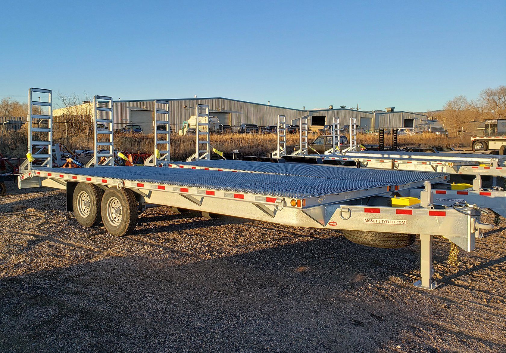 A trailer is parked in a gravel lot in front of a building.