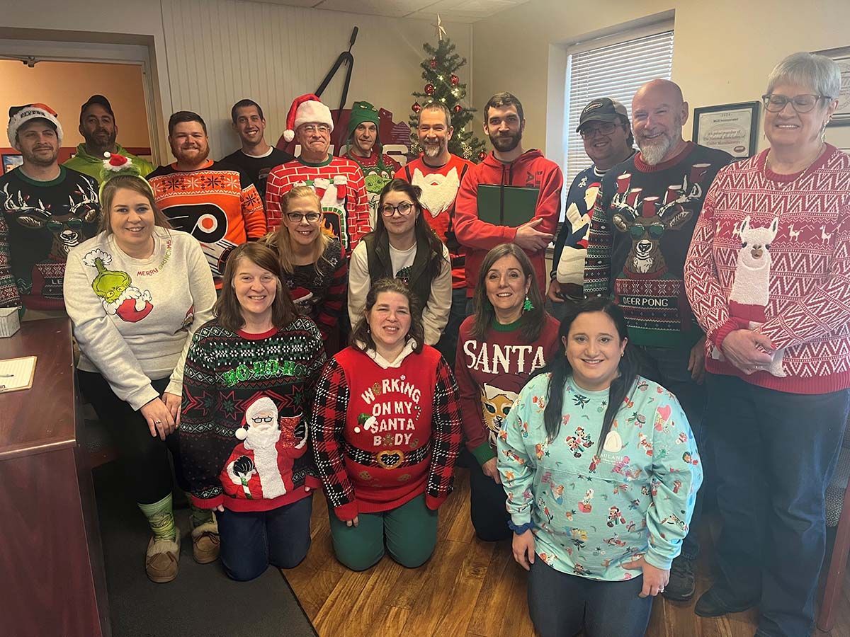 A group of people wearing christmas sweaters are posing for a picture.