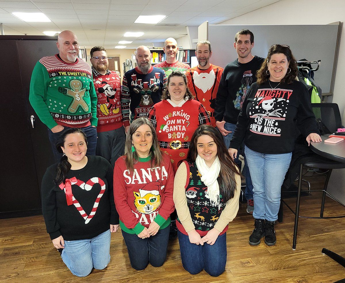 A group of people wearing christmas sweaters are posing for a picture.