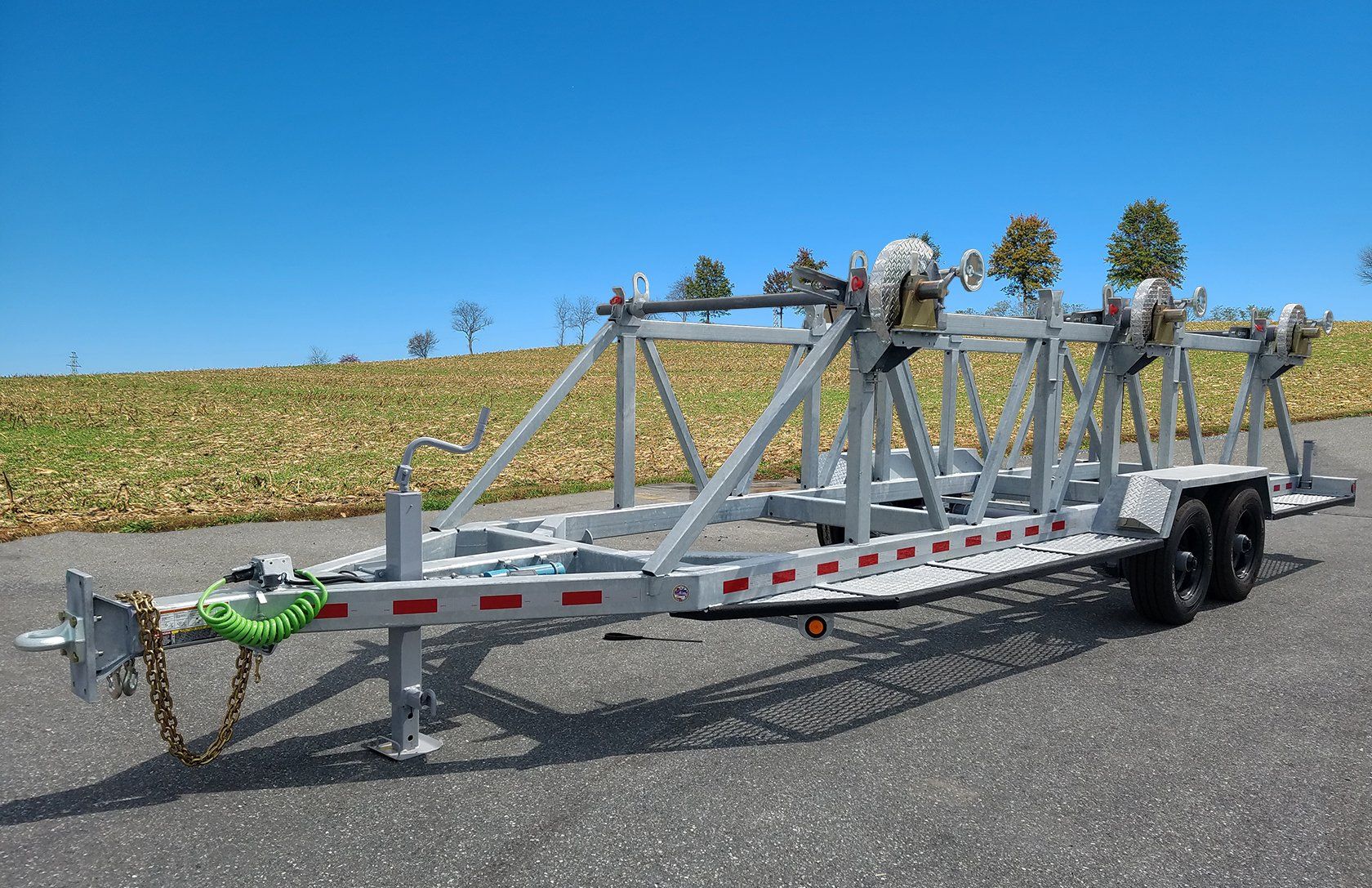 A trailer is parked on the side of the road in front of a field.