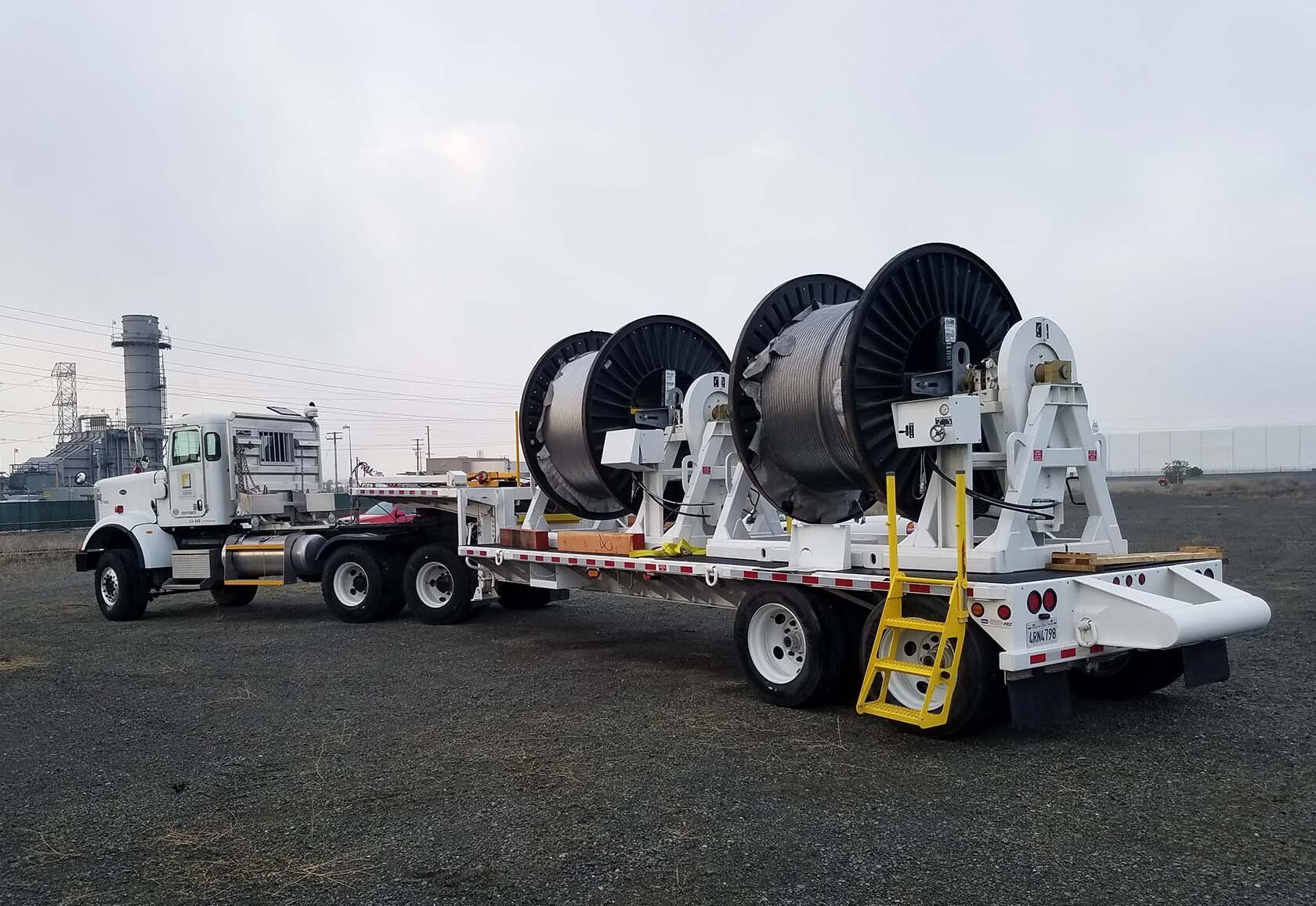A truck is pulling a trailer with a bunch of spools on it.