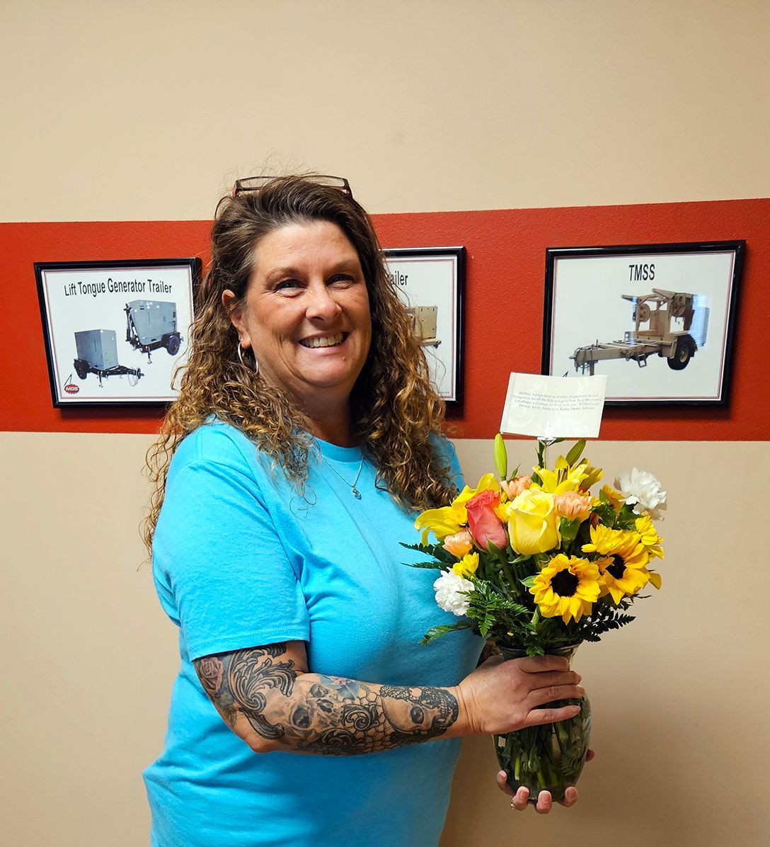 A woman in a blue shirt is holding a bouquet of flowers