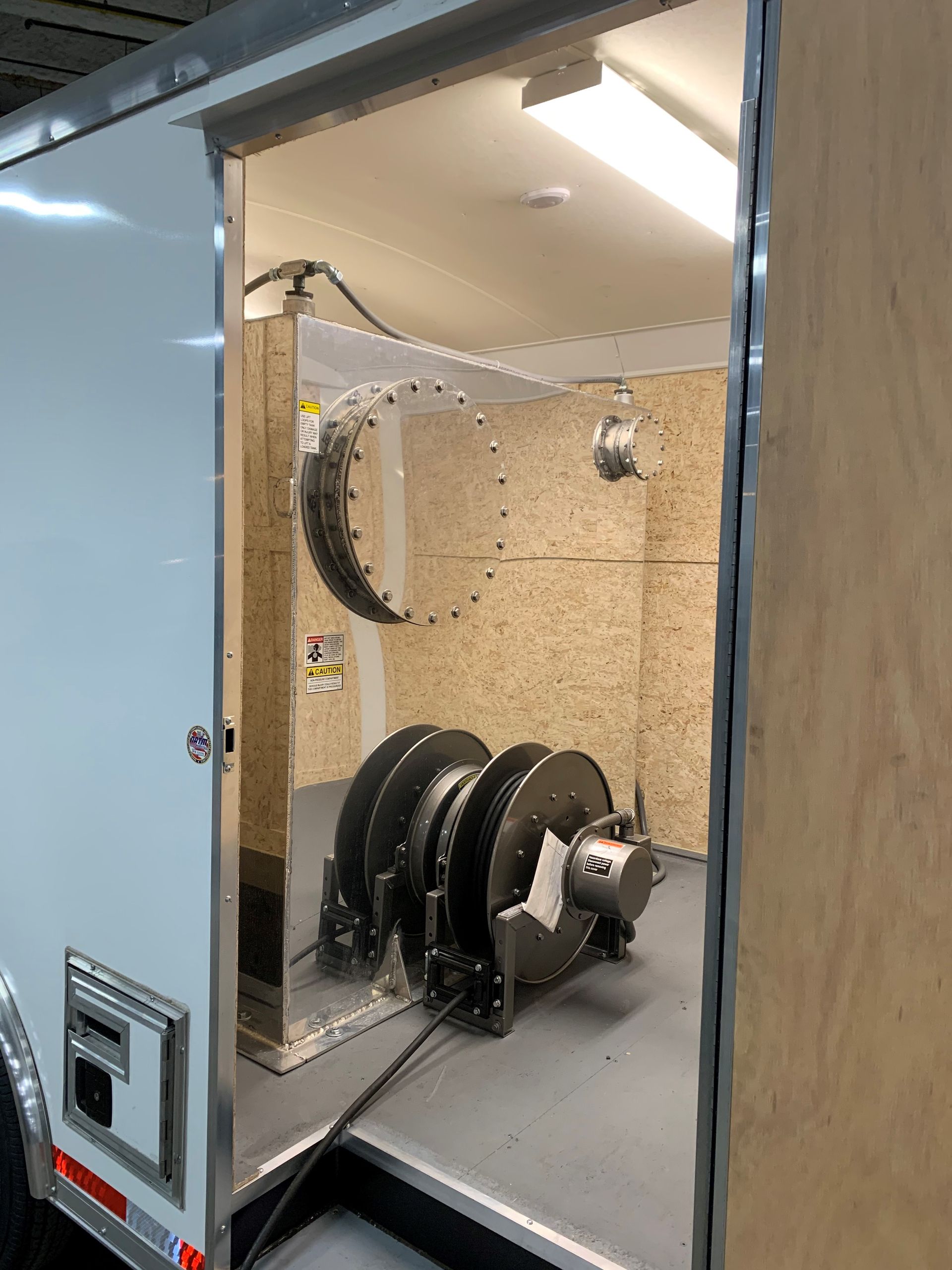 A trailer with a bunch of hose reels inside of it.