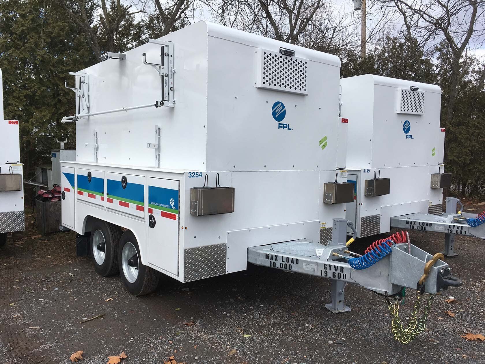 Two white trailers are parked next to each other in a gravel lot.