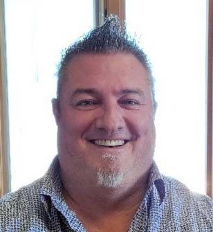 A man with a beard and mohawk is smiling for the camera.