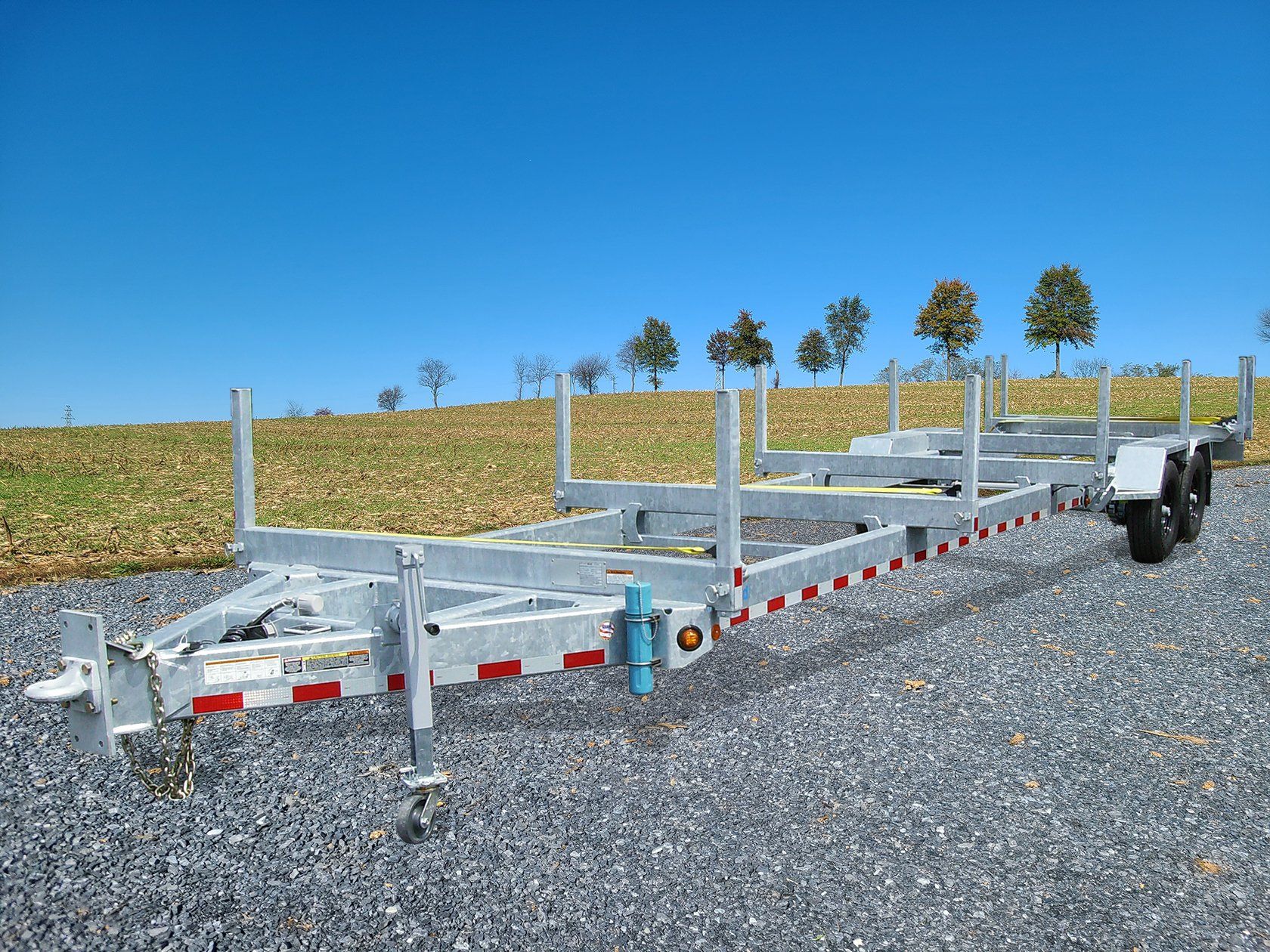 A trailer is parked on gravel in front of a field.