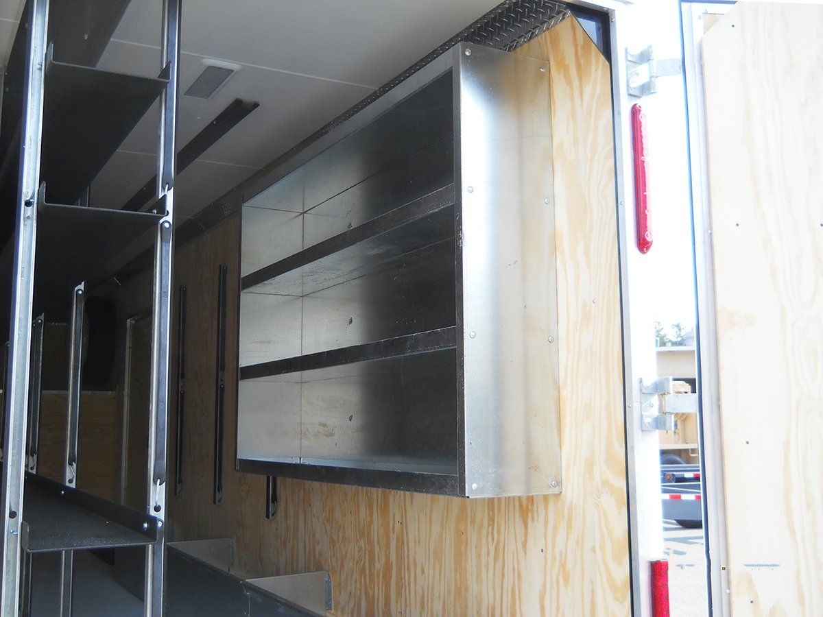The inside of a trailer with shelves and a red tail light