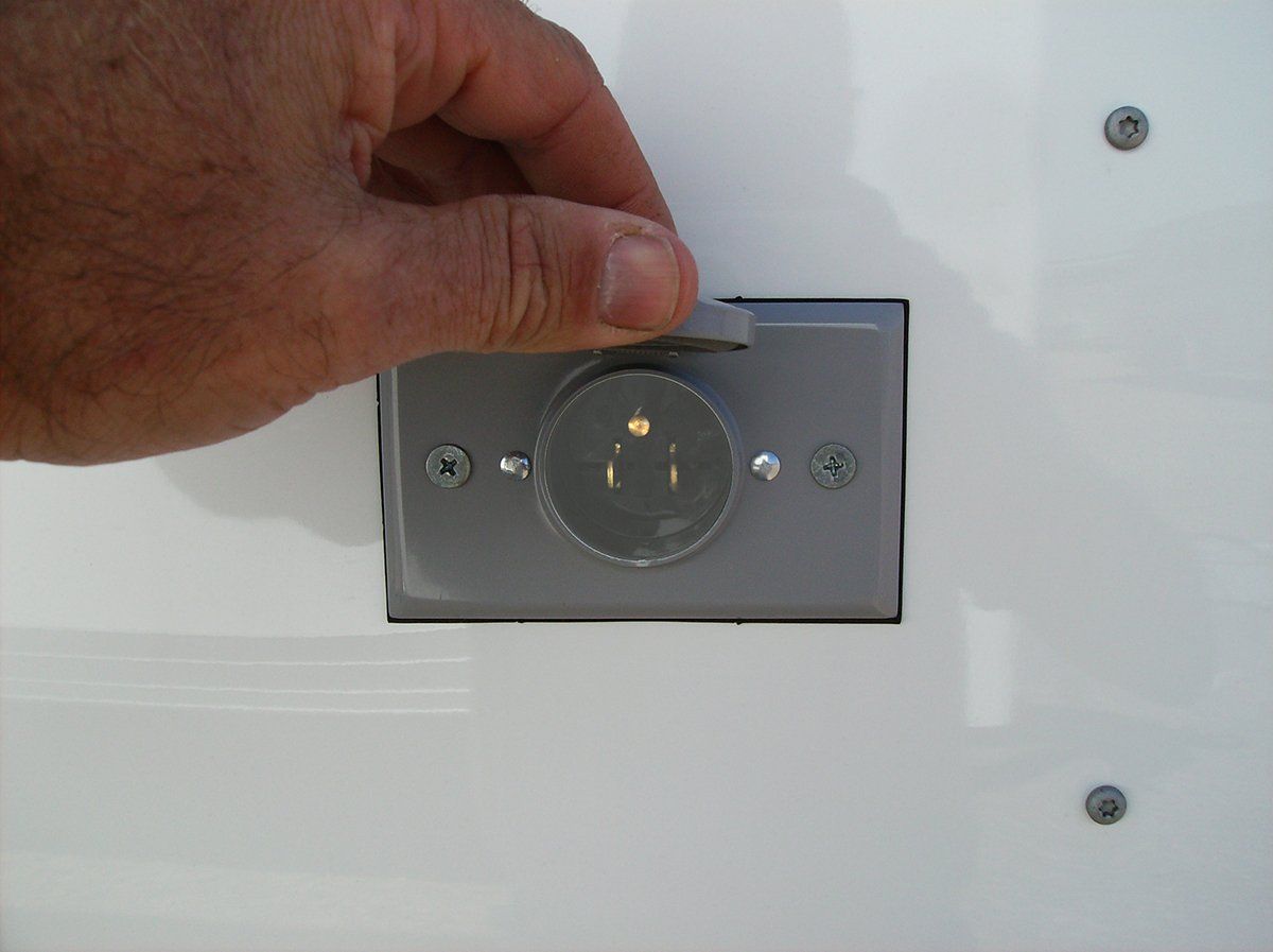 A person is plugging a plug into a wall outlet