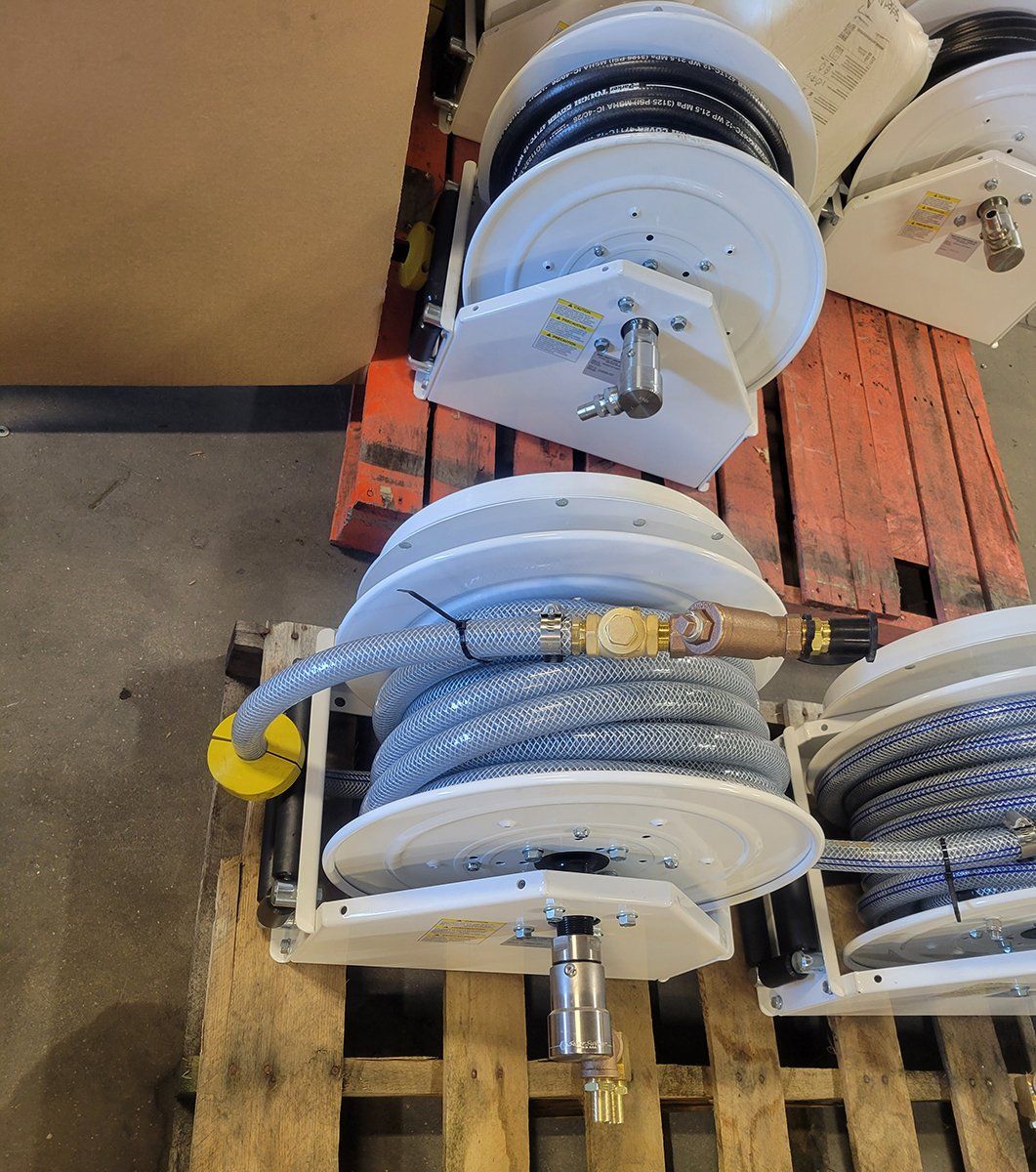 A bunch of hose reels are sitting on top of a wooden pallet.