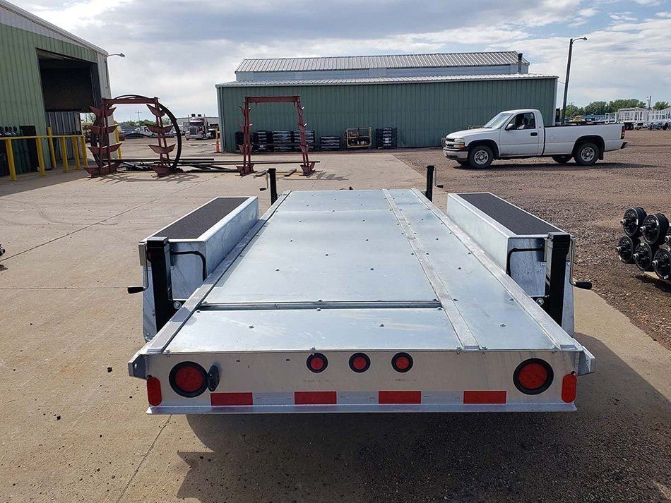 A white truck is parked next to a trailer in a parking lot.