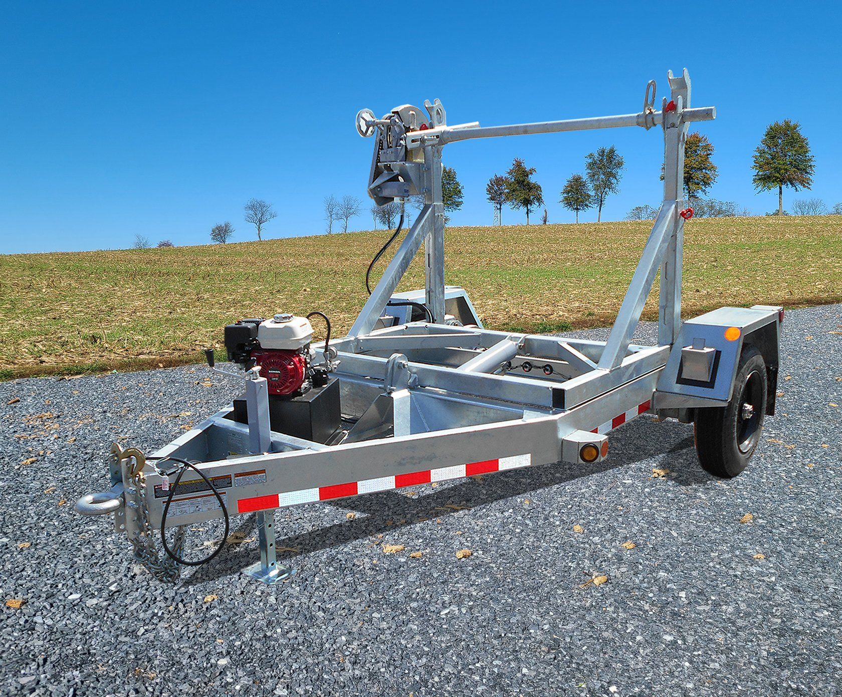 A trailer is parked on gravel in front of a field.