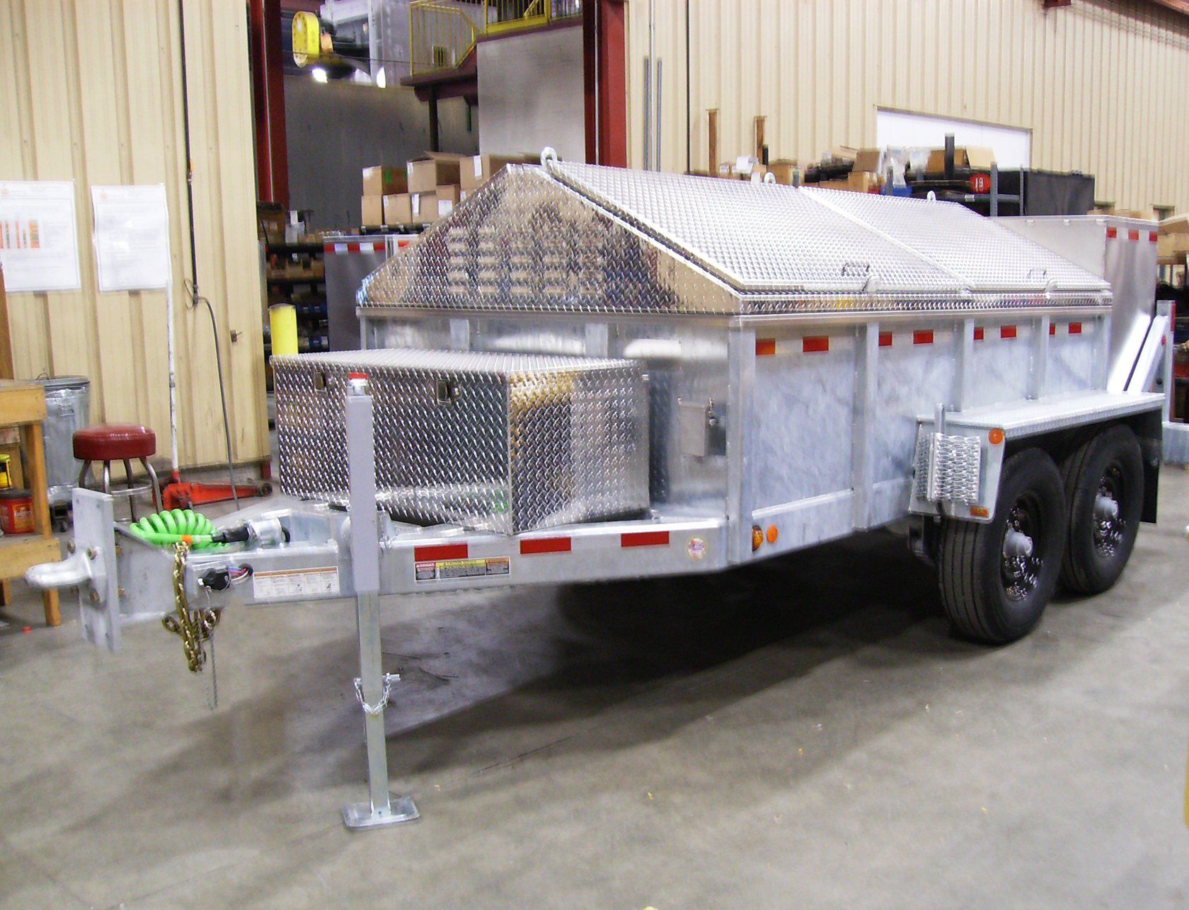 A dump trailer is parked in a warehouse with the door open