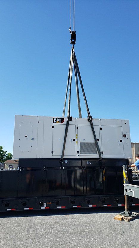 A large generator is being lifted by a crane.