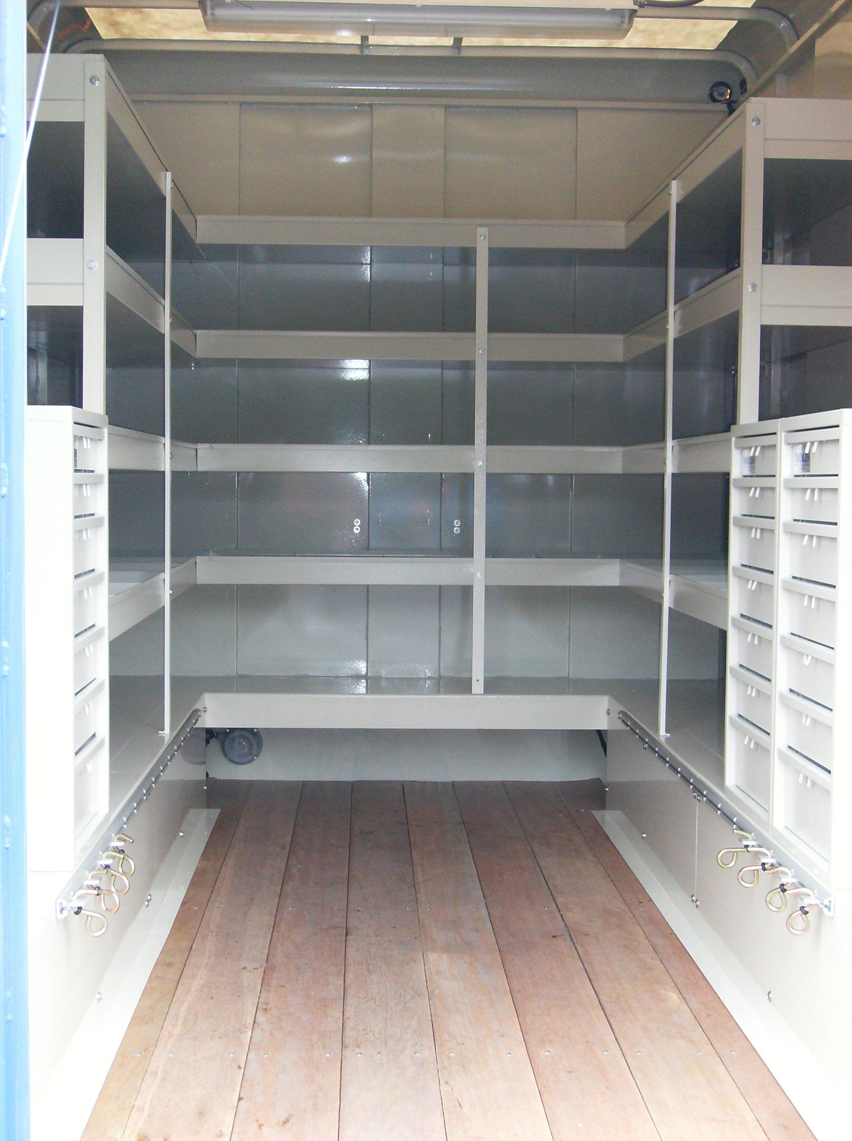The inside of a truck with shelves and a wooden floor