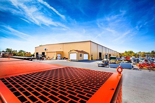 A large orange tractor is parked in front of a large building.