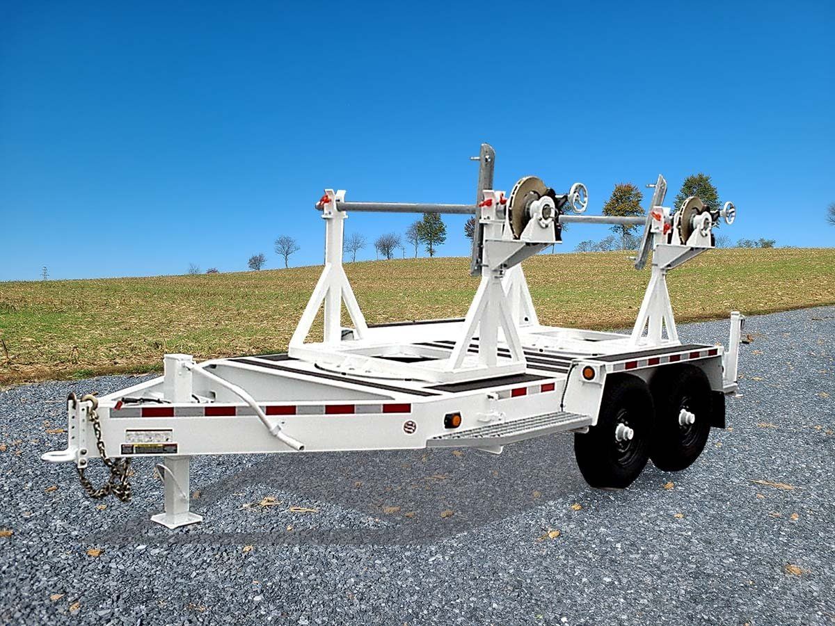 A white trailer is parked on gravel next to a field.