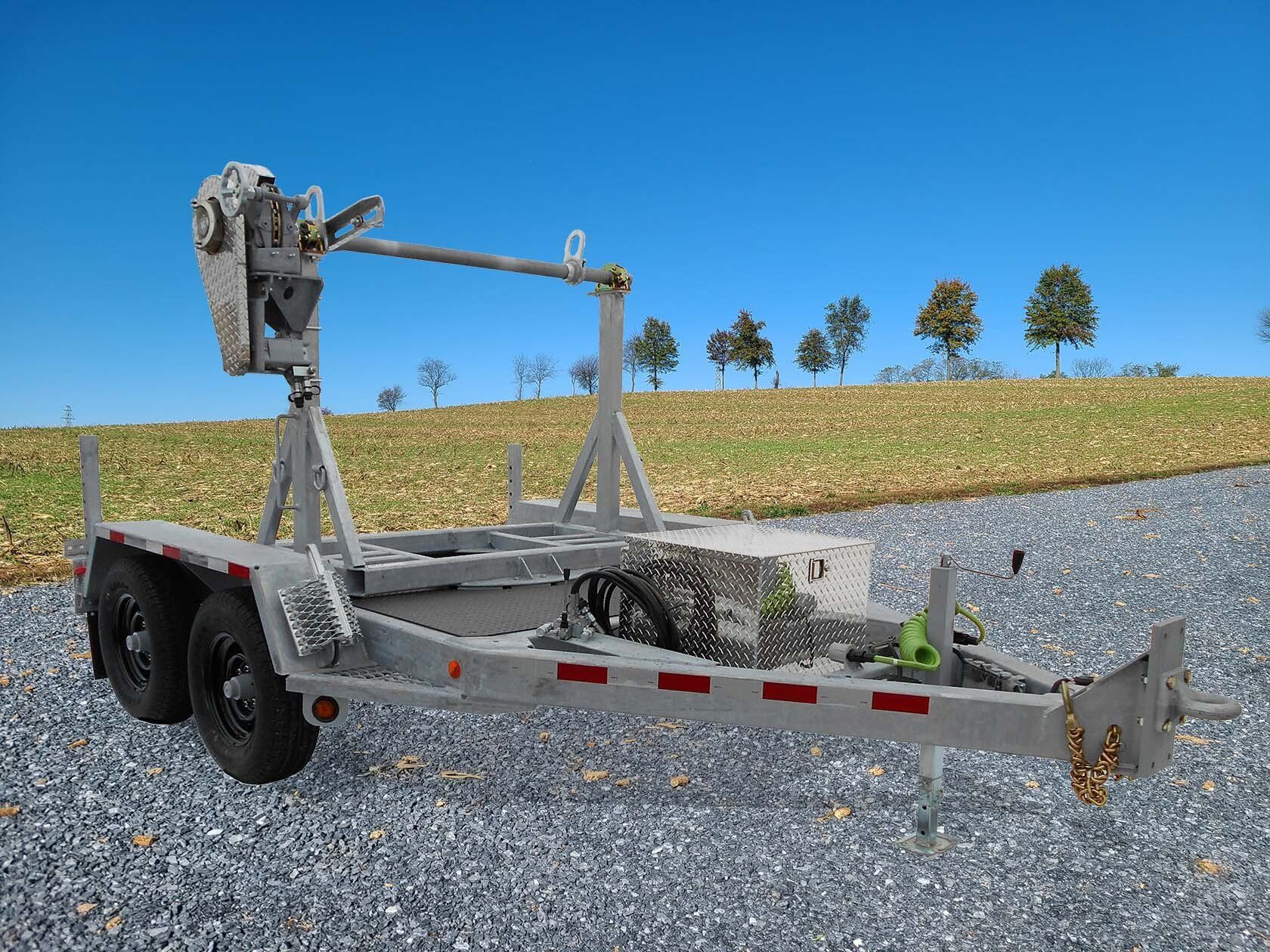 A trailer with a ladder attached to it is parked on a gravel road.