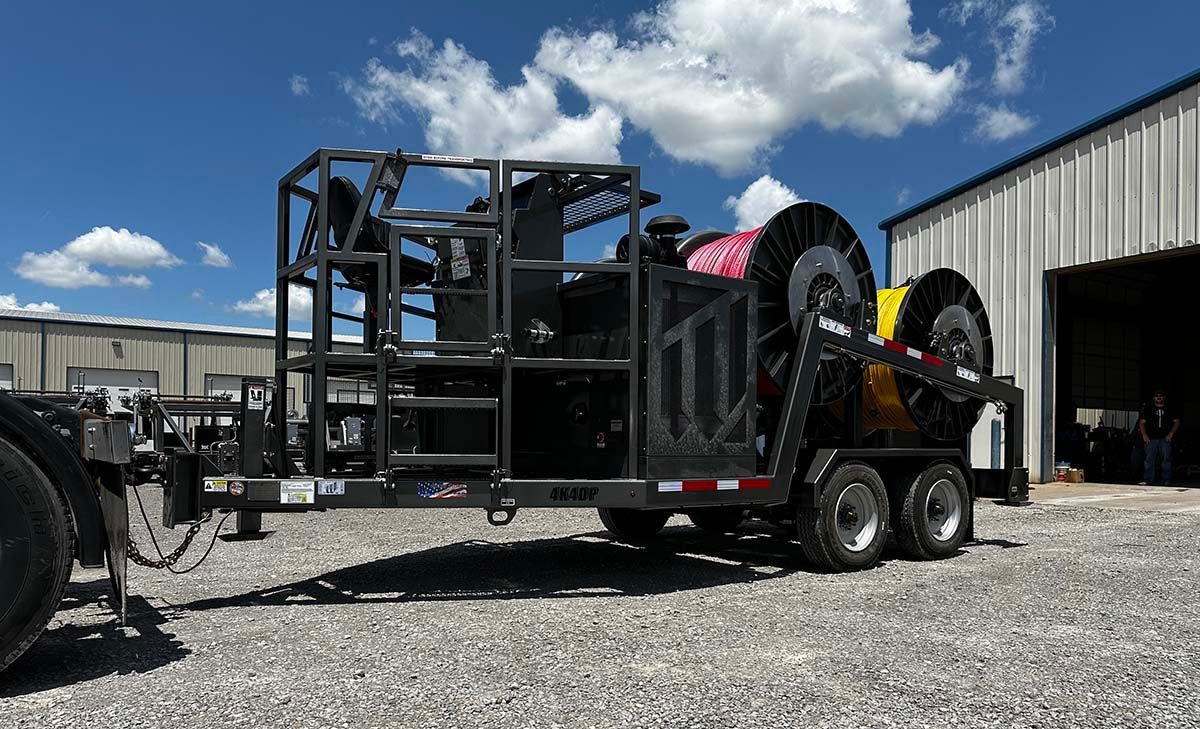 A trailer with a bunch of hose on it is parked in front of a building.