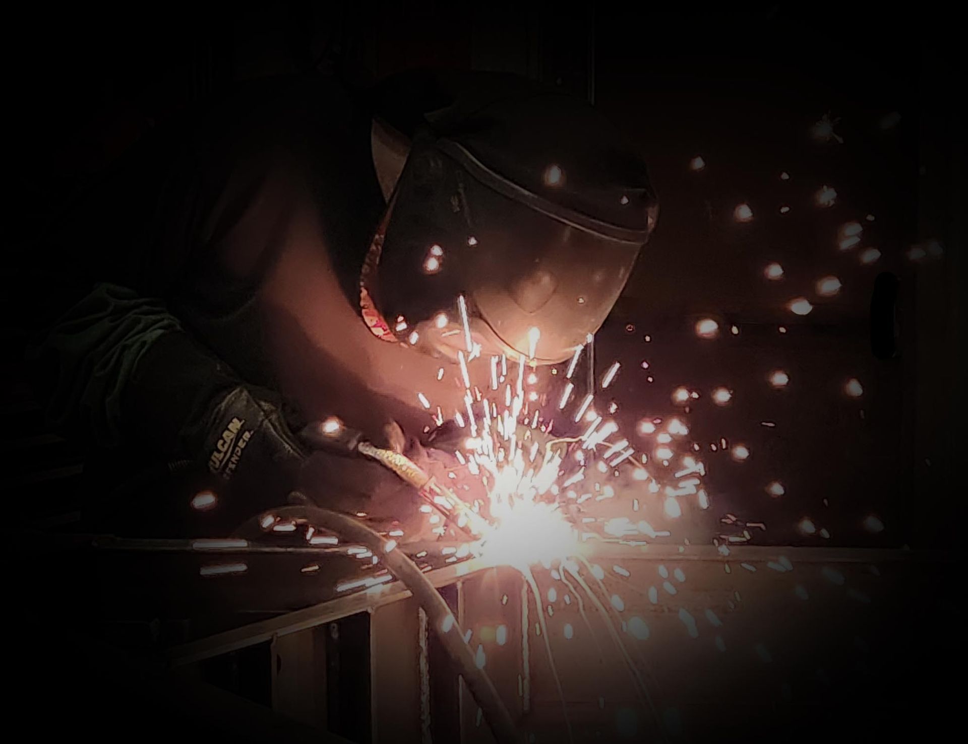 A man is welding a piece of metal in a factory.