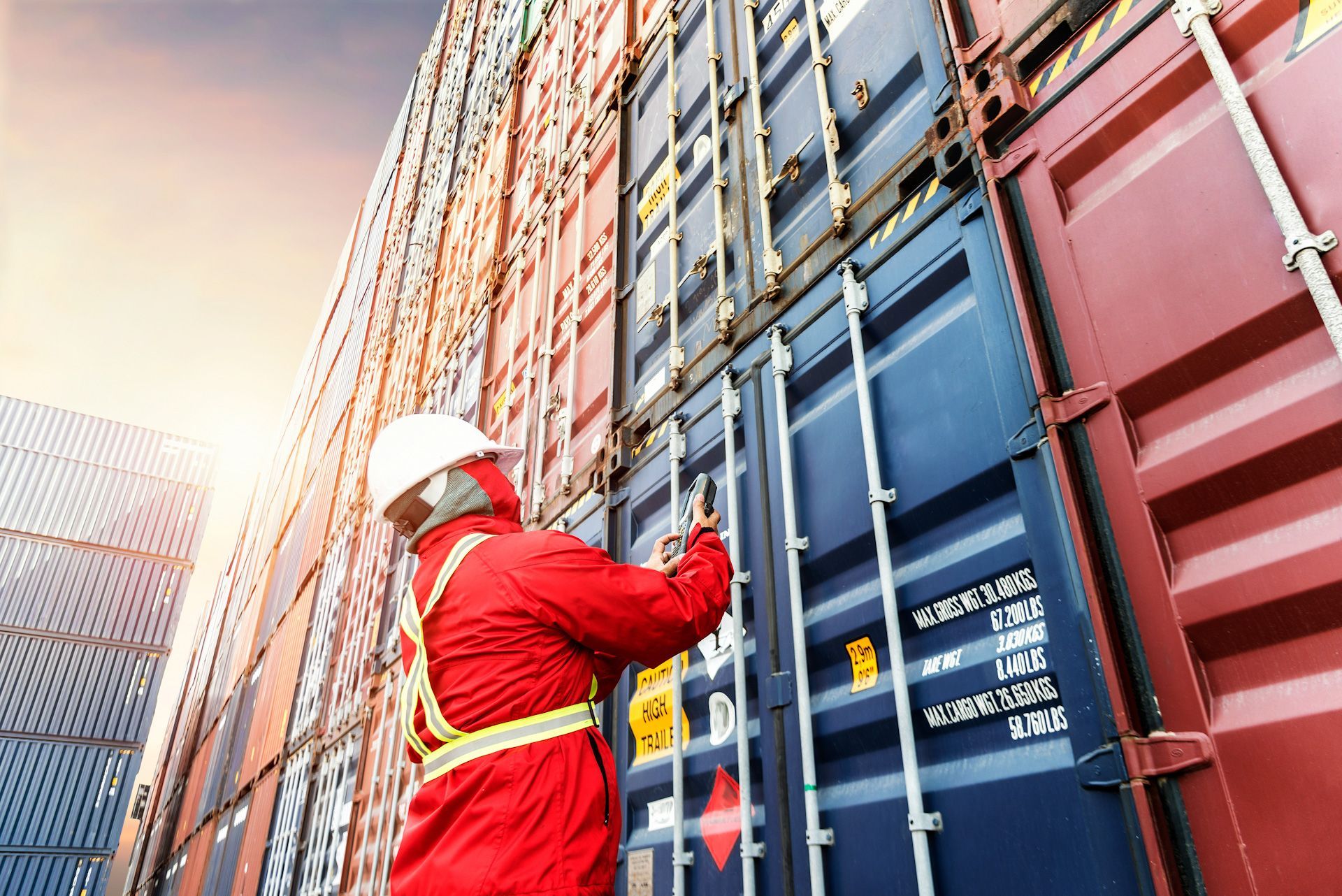 A man is standing next to a stack of shipping containers.