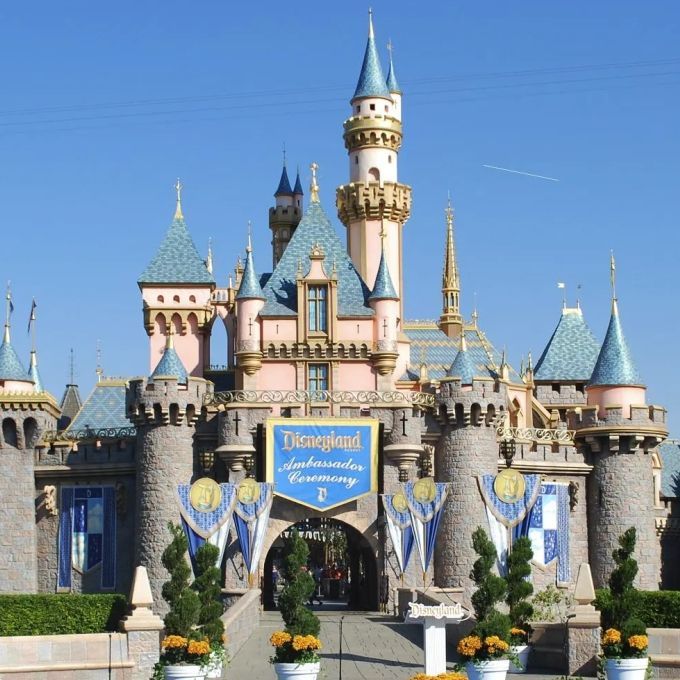 Sleeping Beauty Castle at Disneyland, with blue and pink turrets, set against a clear blue sky.