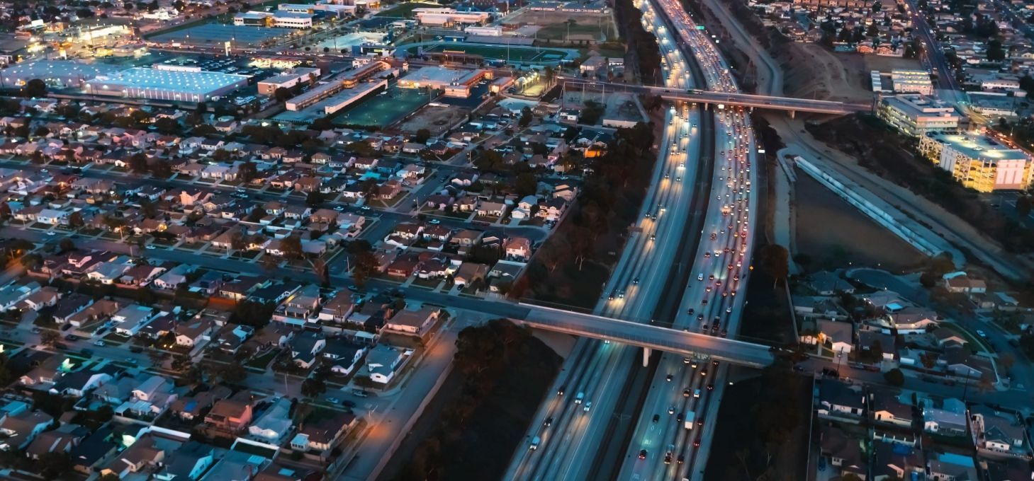 Aerial view of city with freeway traffic at night. Lit streets and buildings are visible.