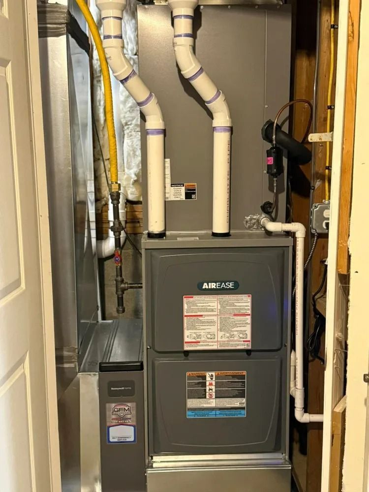 A furnace is sitting in a corner of a room next to a door.