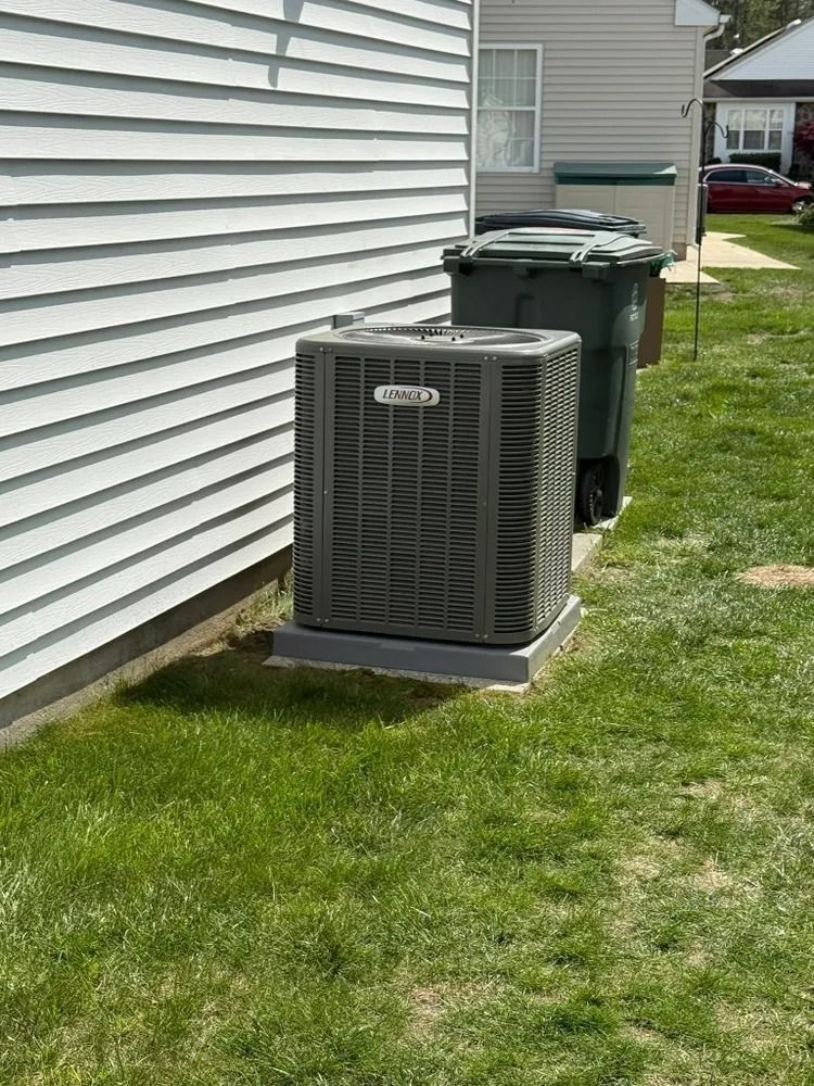 A large air conditioner is sitting in the grass next to a house.