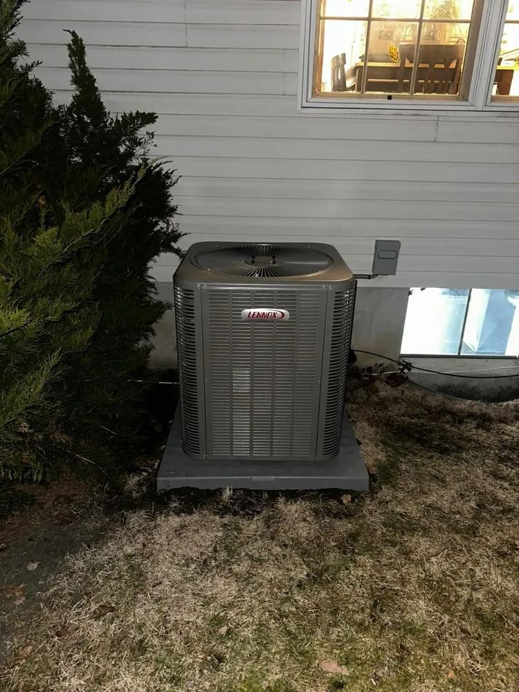 An air conditioner is sitting outside of a house next to a window.
